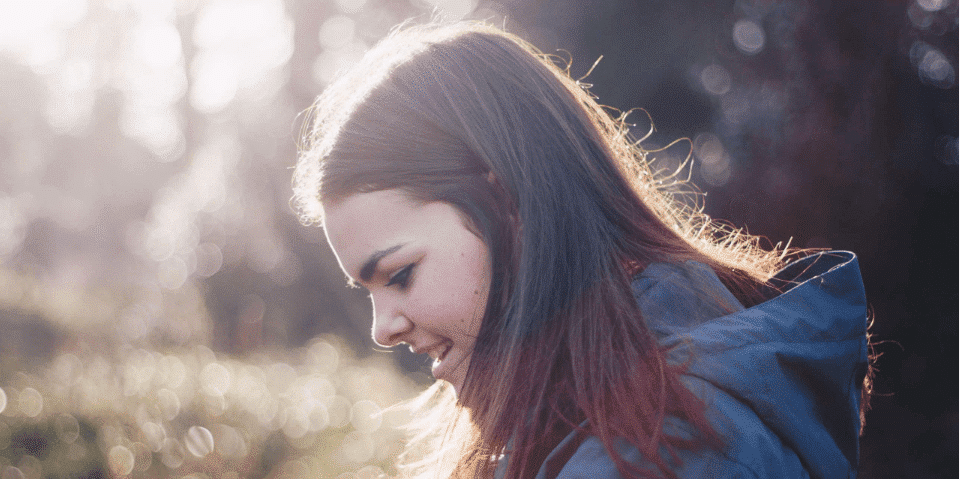 Woman standing in forest with sun shining