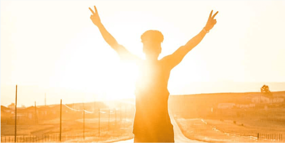 Man standing on a road with the sun behind him